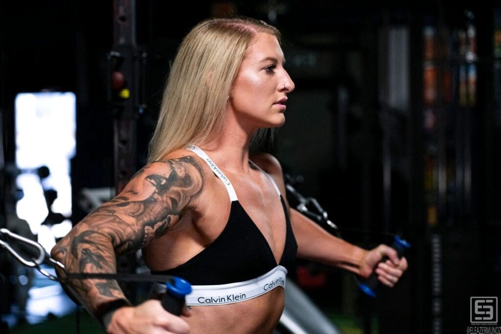 Cami Bee stands on green turf holding cable handles together in front of her.