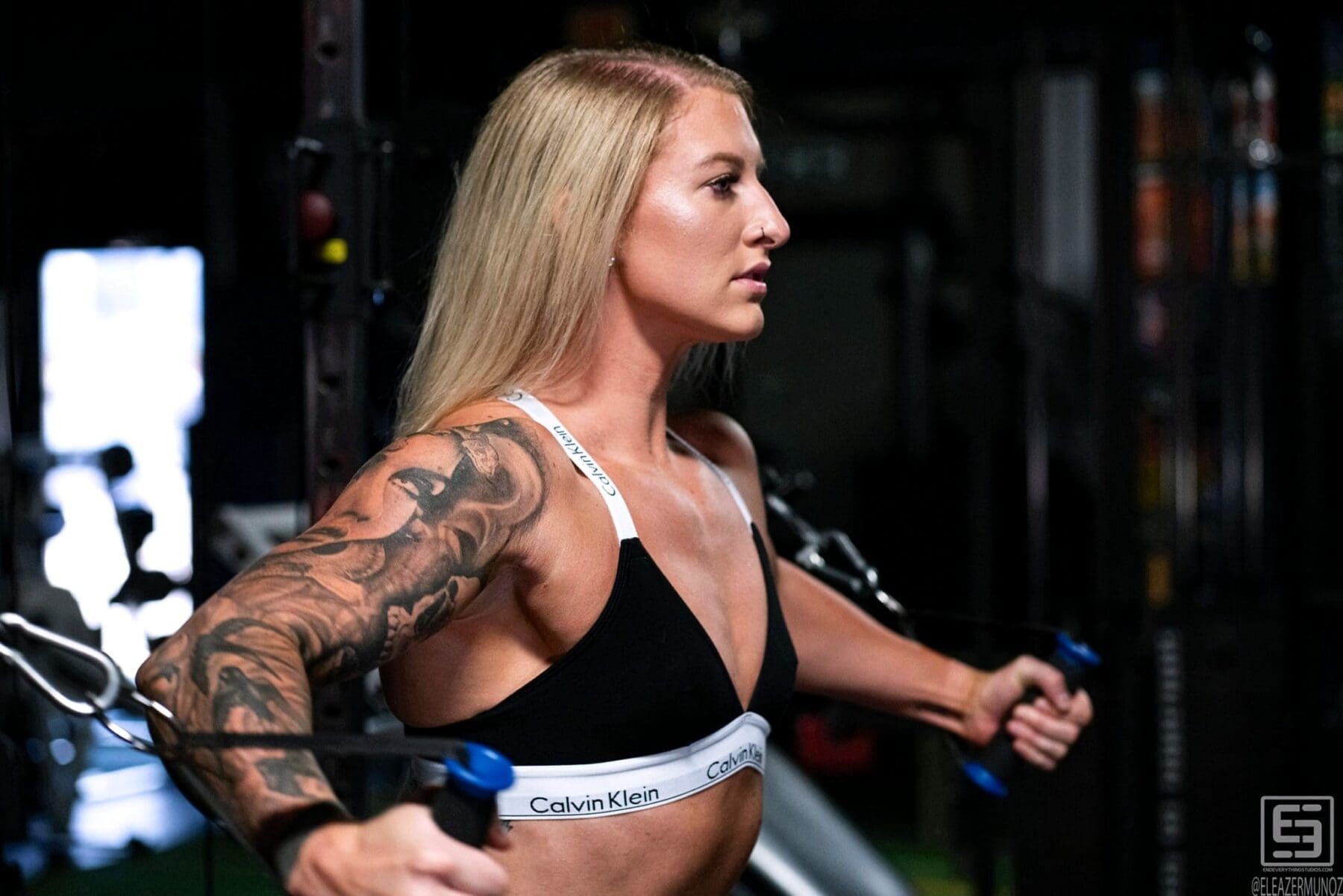 Cami Bee stands on green turf holding cable handles together in front of her.