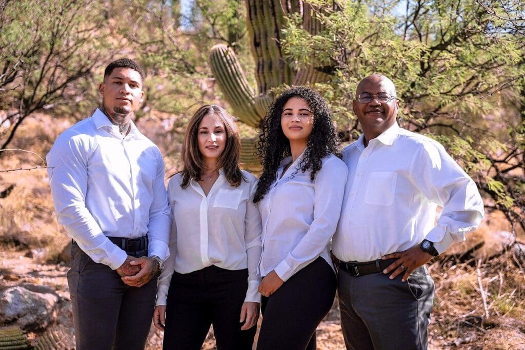 Four family members stand close together in coordinated white shirts among desert vegetation.