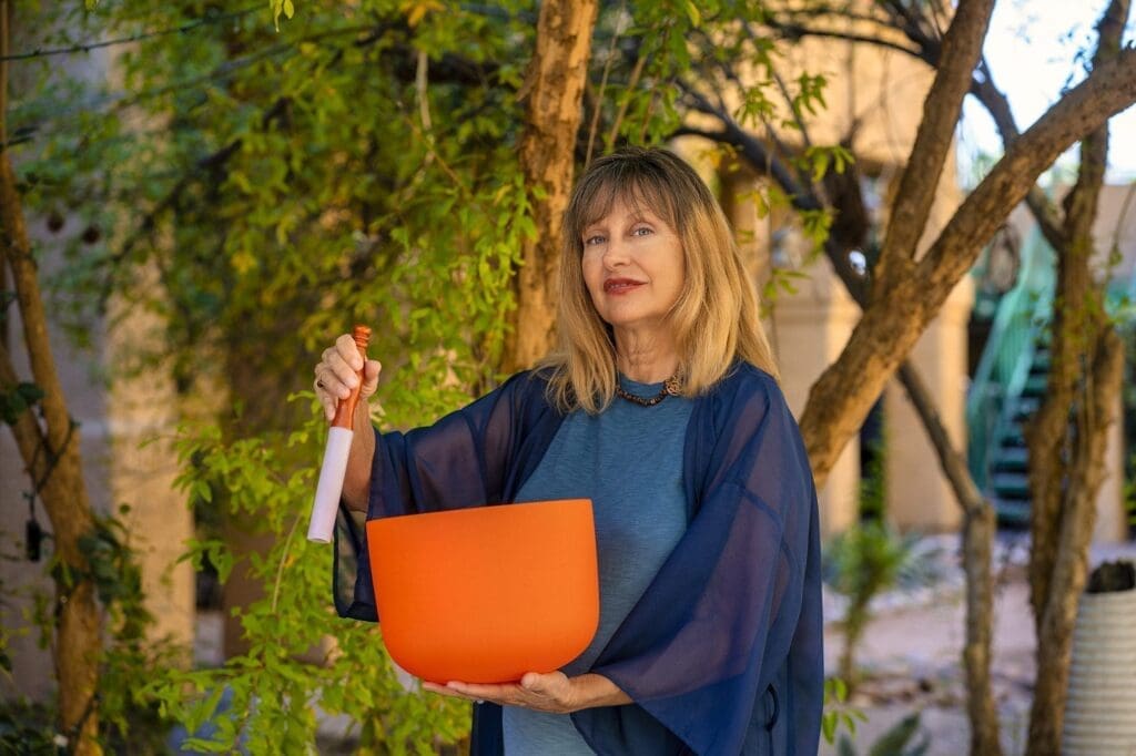 Kat Styrcula holds an orange crystal sound bowl during a sound-therapy portrait session.