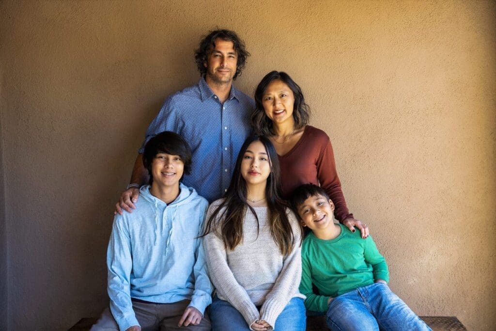 Five members of the Simpkins family sit and stand together against an adobe-colored wall.