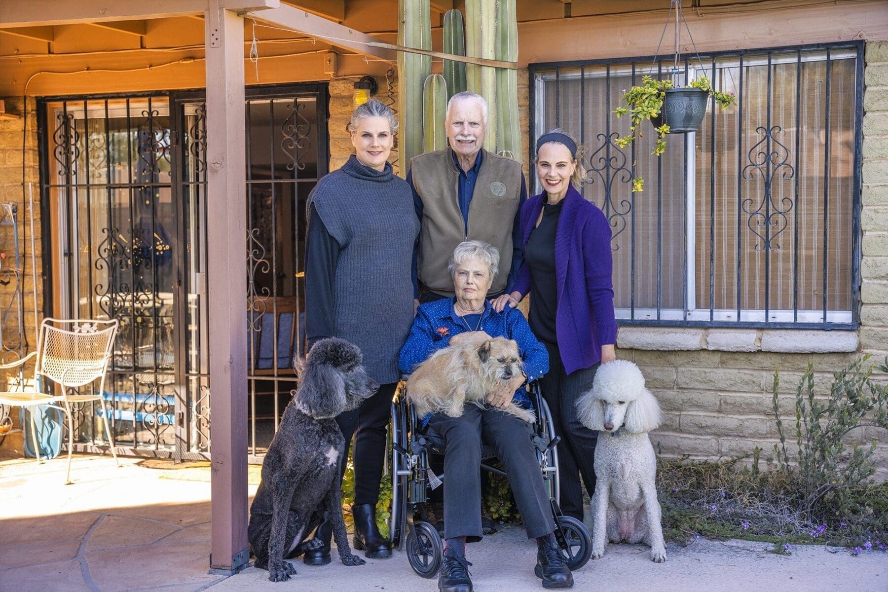 The Slack family poses together with three dogs by a shaded porch during a Mother’s Day gift photo session.
