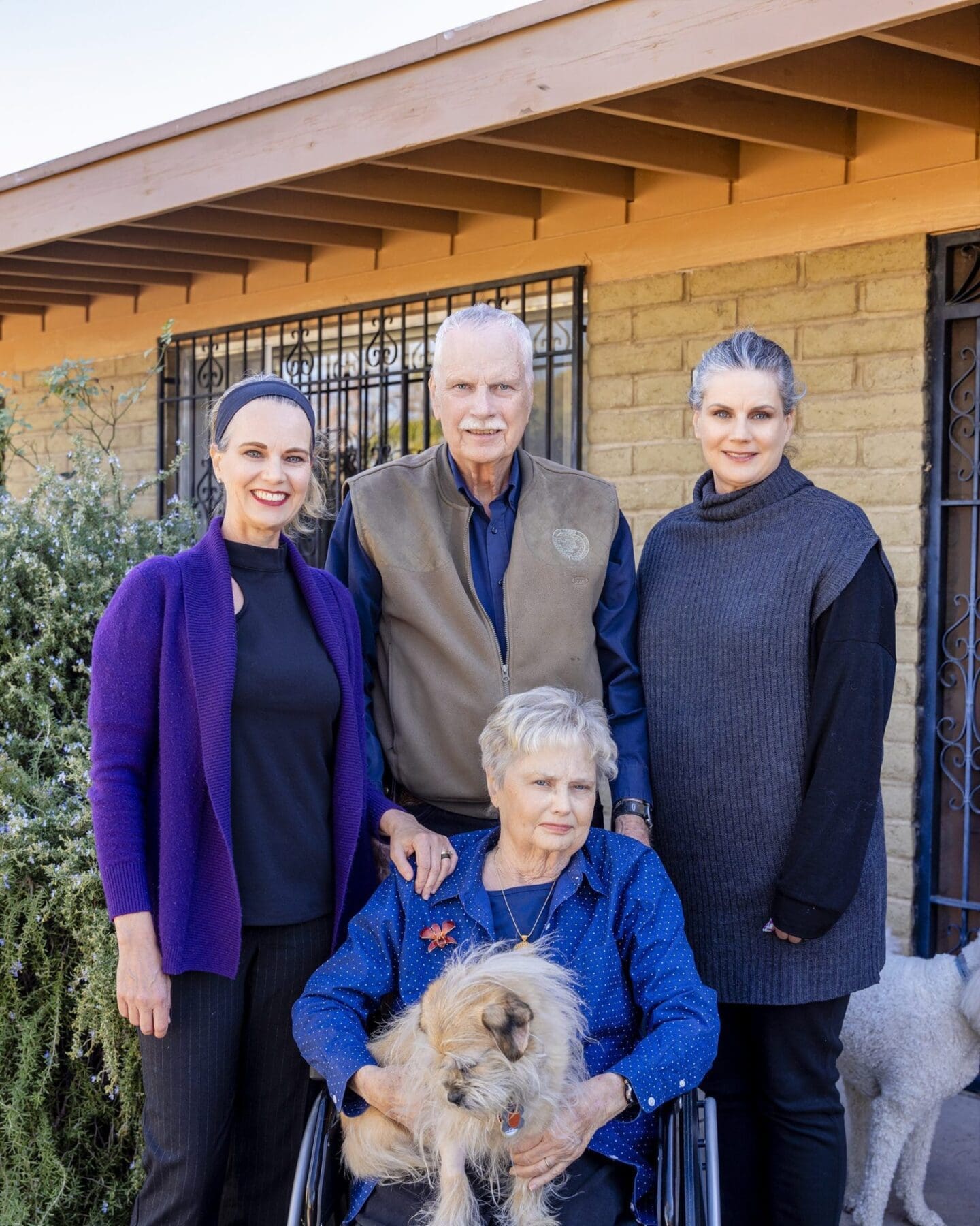 Four Slack family members pose by a brick exterior with a dog in front.