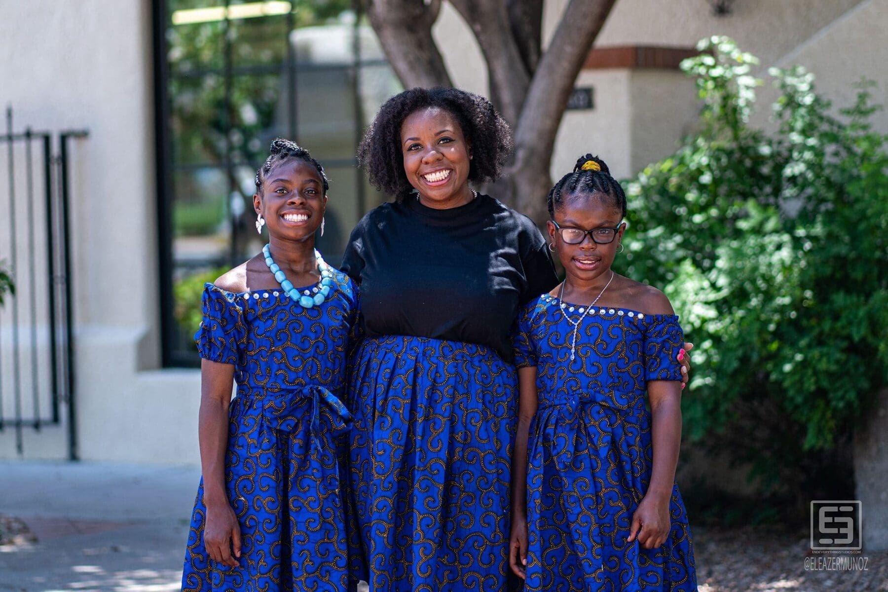 Three young women pose together in coordinated blue patterned clothing.