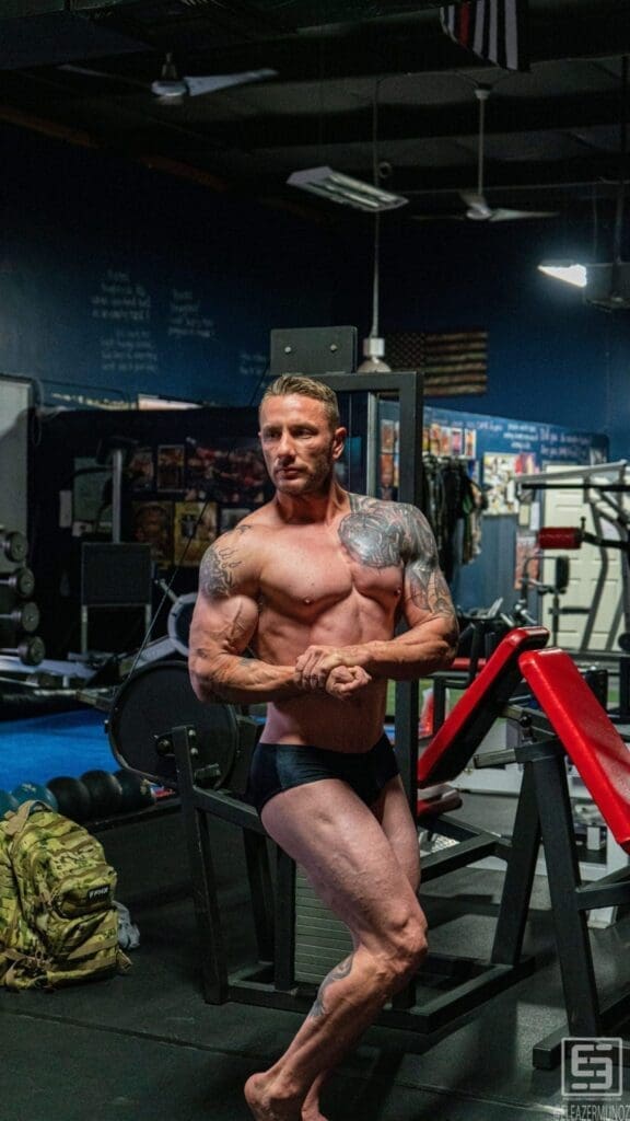 Irish Michael displays a side-chest pose in a vertical portrait showing his torso and legs.