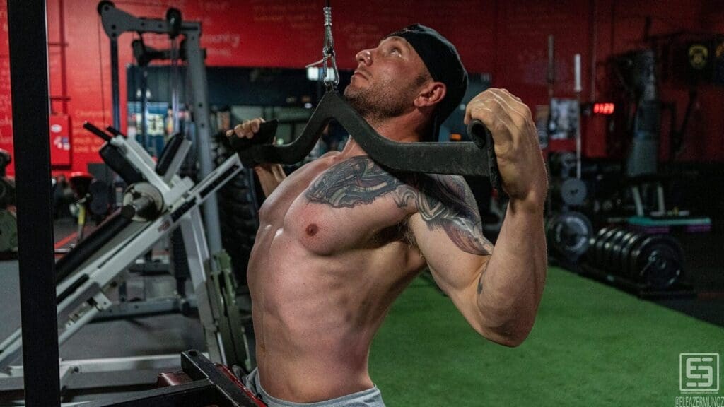 Irish Michael pulls a wide bar toward his upper chest during a seated lat-pulldown exercise.