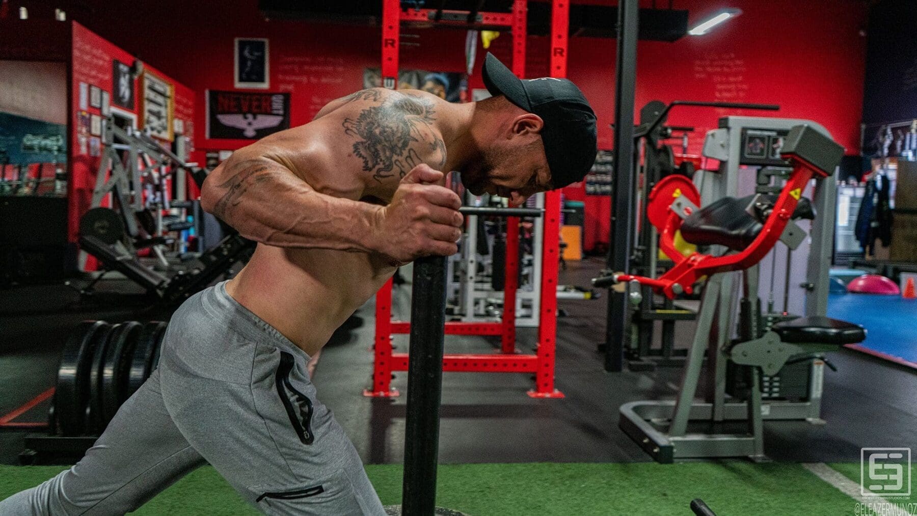 Irish Michael leans forcefully into the handles of a weighted sled during a close side view.